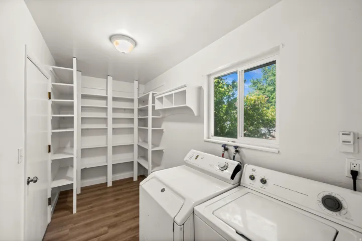 Utility room featuring extensive built-in shelving, wood-finish flooring, and a large window