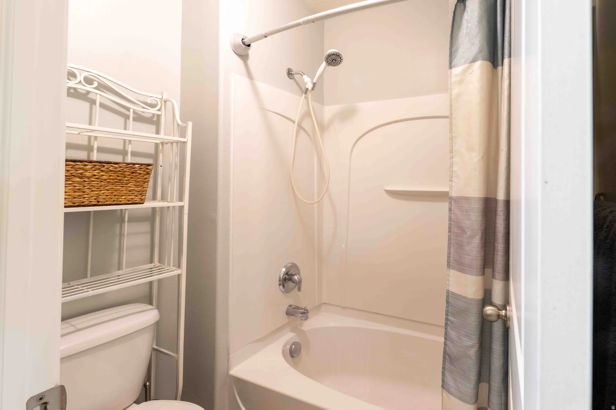 White bathtub/shower combination with integrated shelving, chrome fixtures, and a handheld showerhead