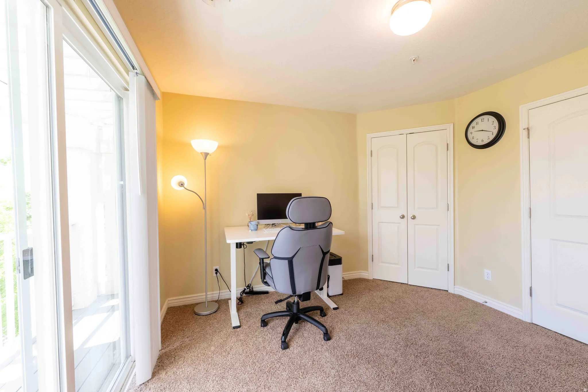 Carpeted room with sliding glass door access to an exterior space, featuring a semi-flush mount ceiling light, white baseboards, and two paneled interior doors