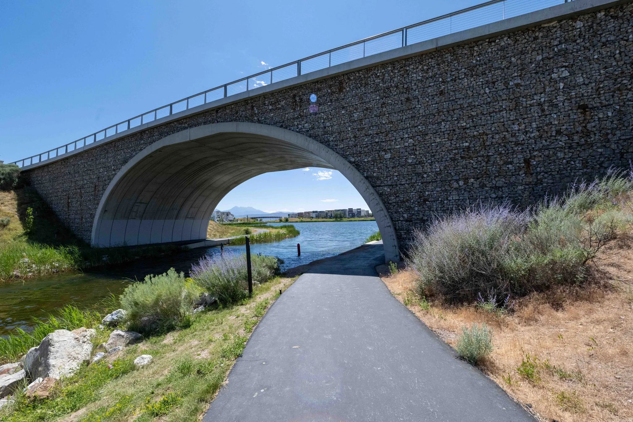 Stone-faced arch bridge spanning a waterway, with a paved pathway beneath