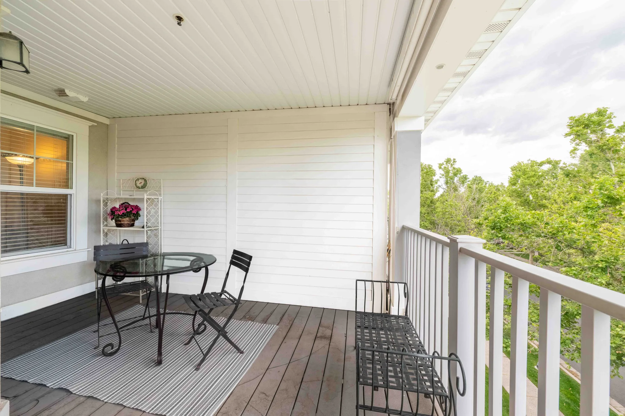 Spacious covered balcony featuring wood-finish flooring, white siding, and a white railing