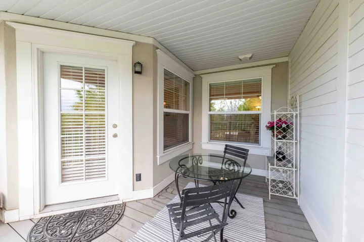 Covered patio featuring a white paneled ceiling, light stucco exterior, and white framed glass-paned door