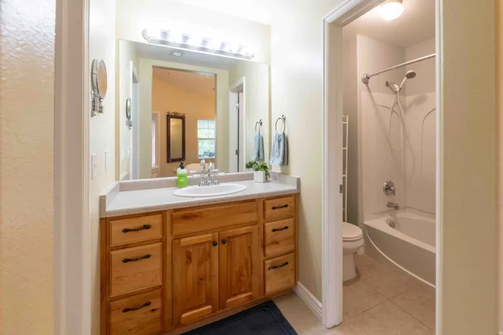 Bathroom vanity featuring a light wood-finish cabinet with multiple drawers and double-door storage, a light-toned countertop, and a large mirror