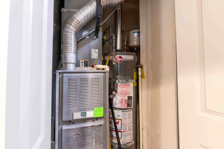 Utility closet with a furnace, water heater, and associated ductwork