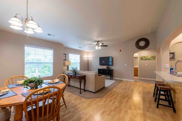 Open-concept living area featuring wood-finish flooring, vaulted ceilings, and natural light from multiple windows