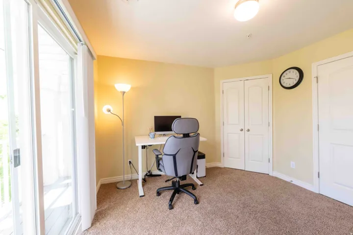 Carpeted room with sliding glass door access to an exterior space, featuring a semi-flush mount ceiling light, white baseboards, and two paneled interior doors