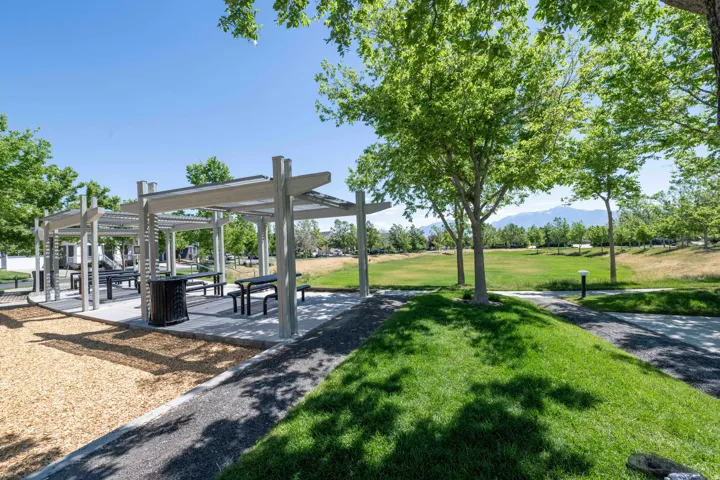 Outdoor pergola structure featuring multiple picnic tables and bench seating