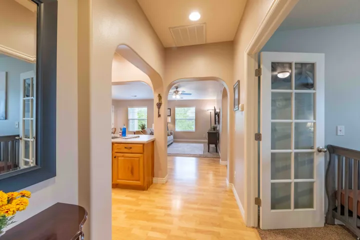 Warm wood-finish flooring extends through an arched entryway into an open-concept living space