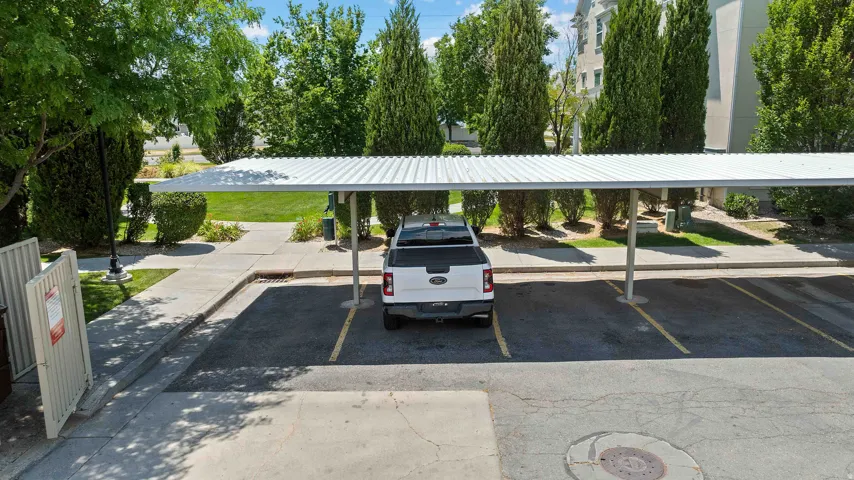 Covered parking structure with a corrugated metal roof over an asphalt lot