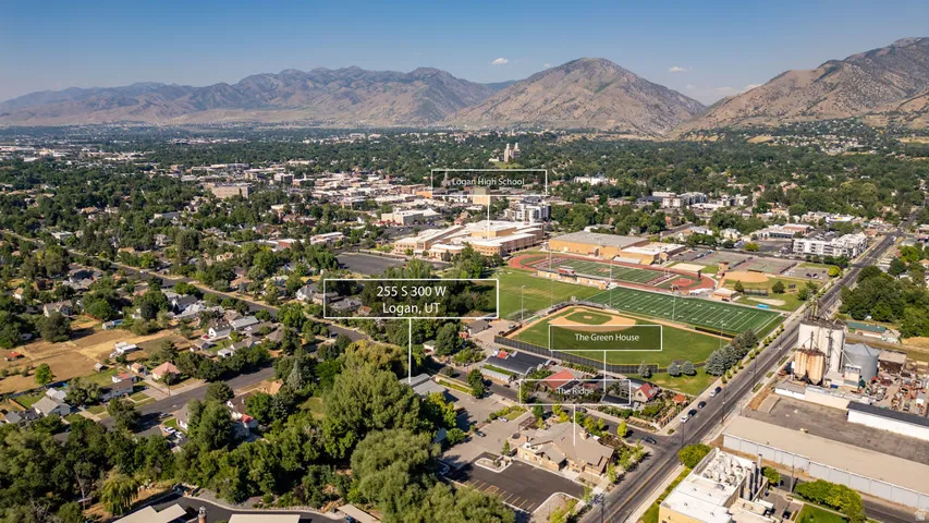 Aerial perspective of a residential area surrounded by mature trees, with mountainous terrain in the background