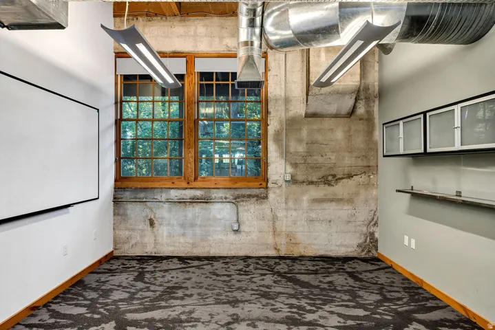Exposed concrete walls paired with hardwood window frames and industrial-style ductwork