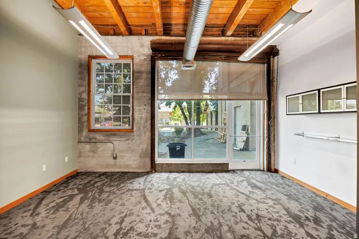 Interior space featuring exposed wood beam ceilings, visible ductwork, and fluorescent lighting