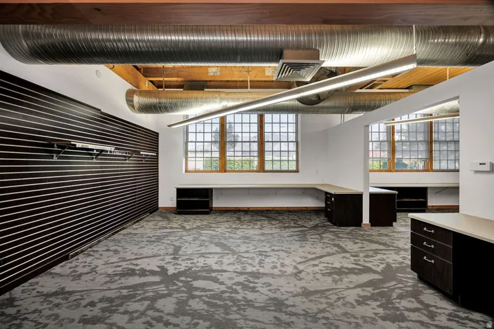 Spacious interior featuring exposed timber beams, industrial-style ductwork, and abundant natural light from multi-pane windows