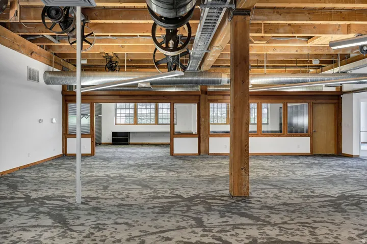 Expansive open-concept space featuring exposed wooden beams and structural columns