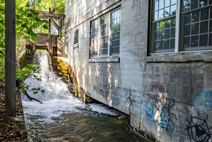 Historic mill structure featuring a working water wheel and visible water flow