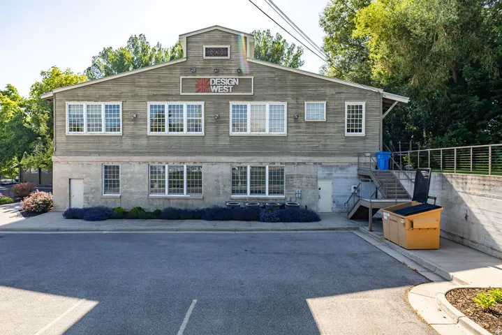 Two-story commercial building featuring wood-panel siding on the upper level and a concrete finish on the lower level