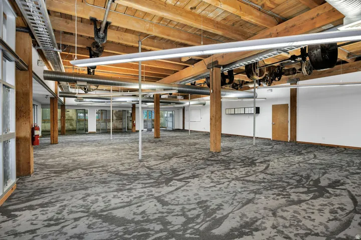 Expansive open-concept space featuring exposed wooden beams and structural columns
