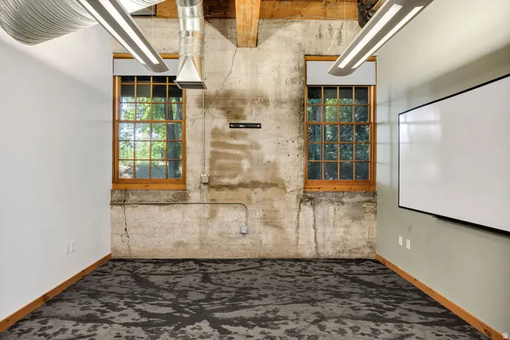 Industrial-style space featuring exposed concrete walls and ceiling beams