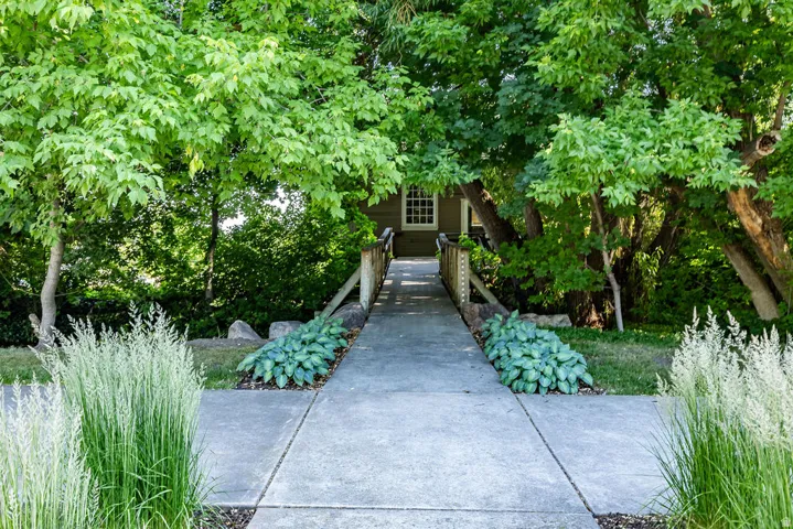 Concrete pathway bordered by ornamental grasses and hosta plantings