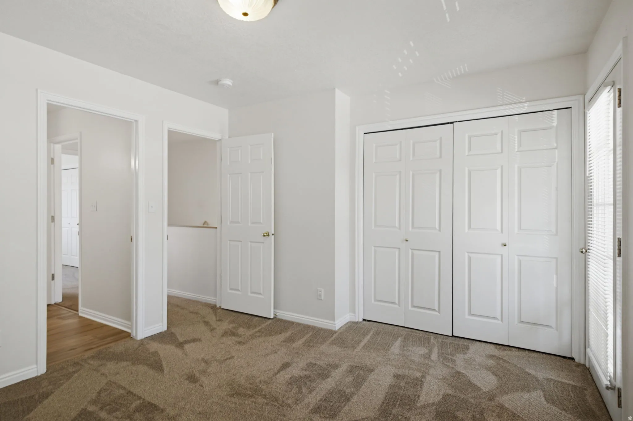 Room featuring neutral-toned carpet, white walls, and a ceiling-mounted light fixture