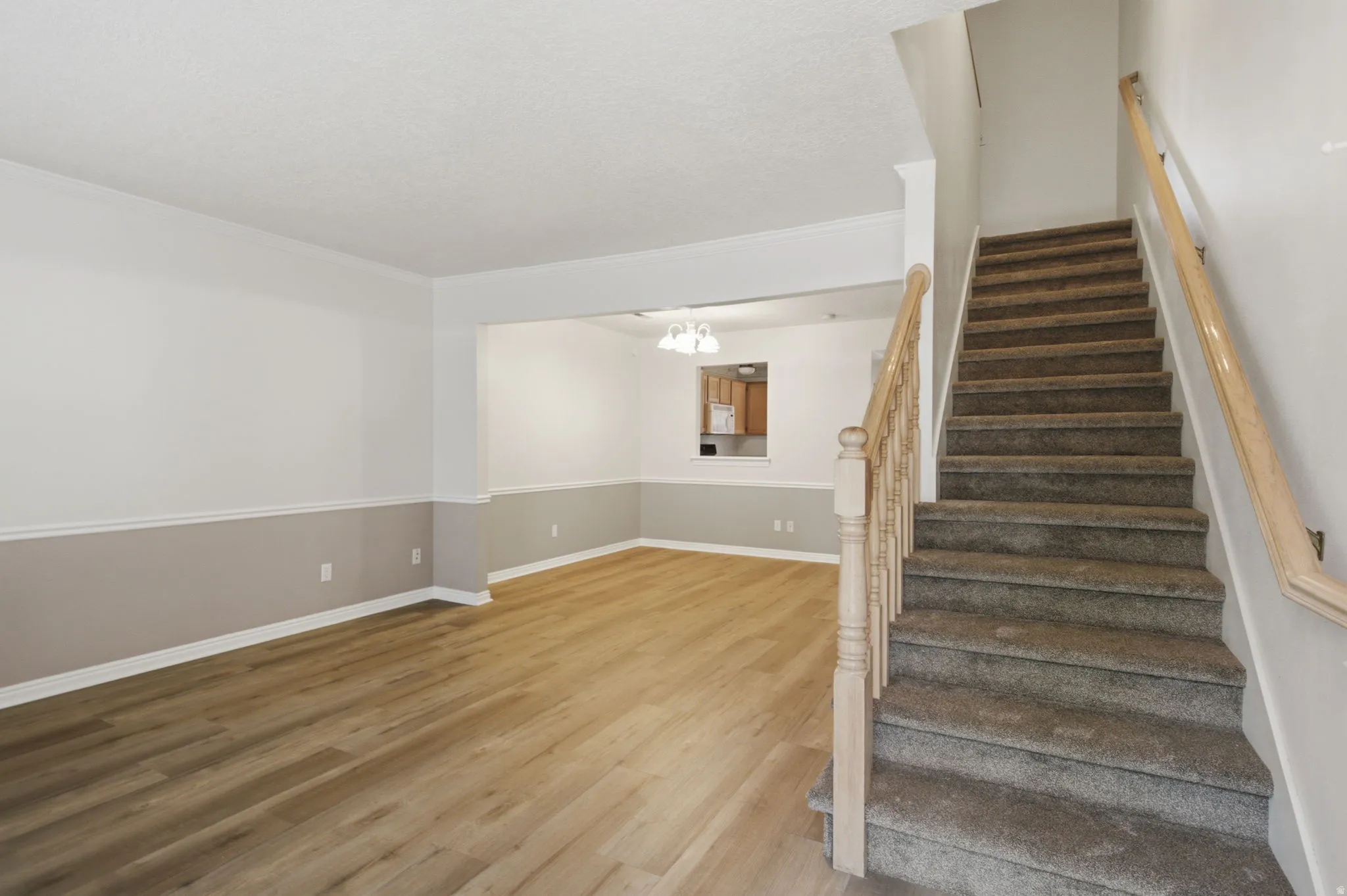 Living area featuring wood-finish flooring, two-tone wall paint, and white baseboards