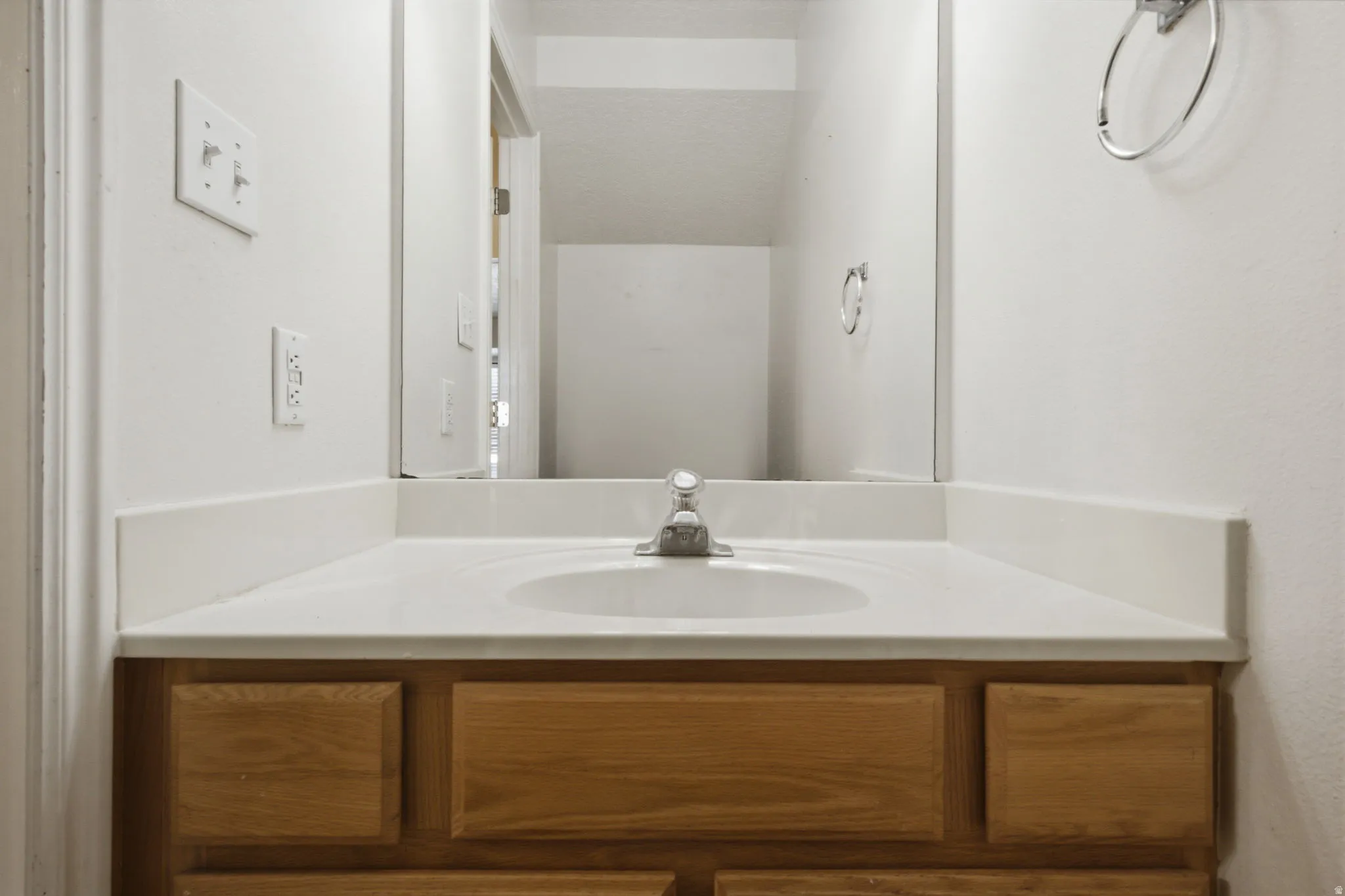 Bathroom vanity featuring an integrated sink, laminate countertop, and wood-finish cabinetry