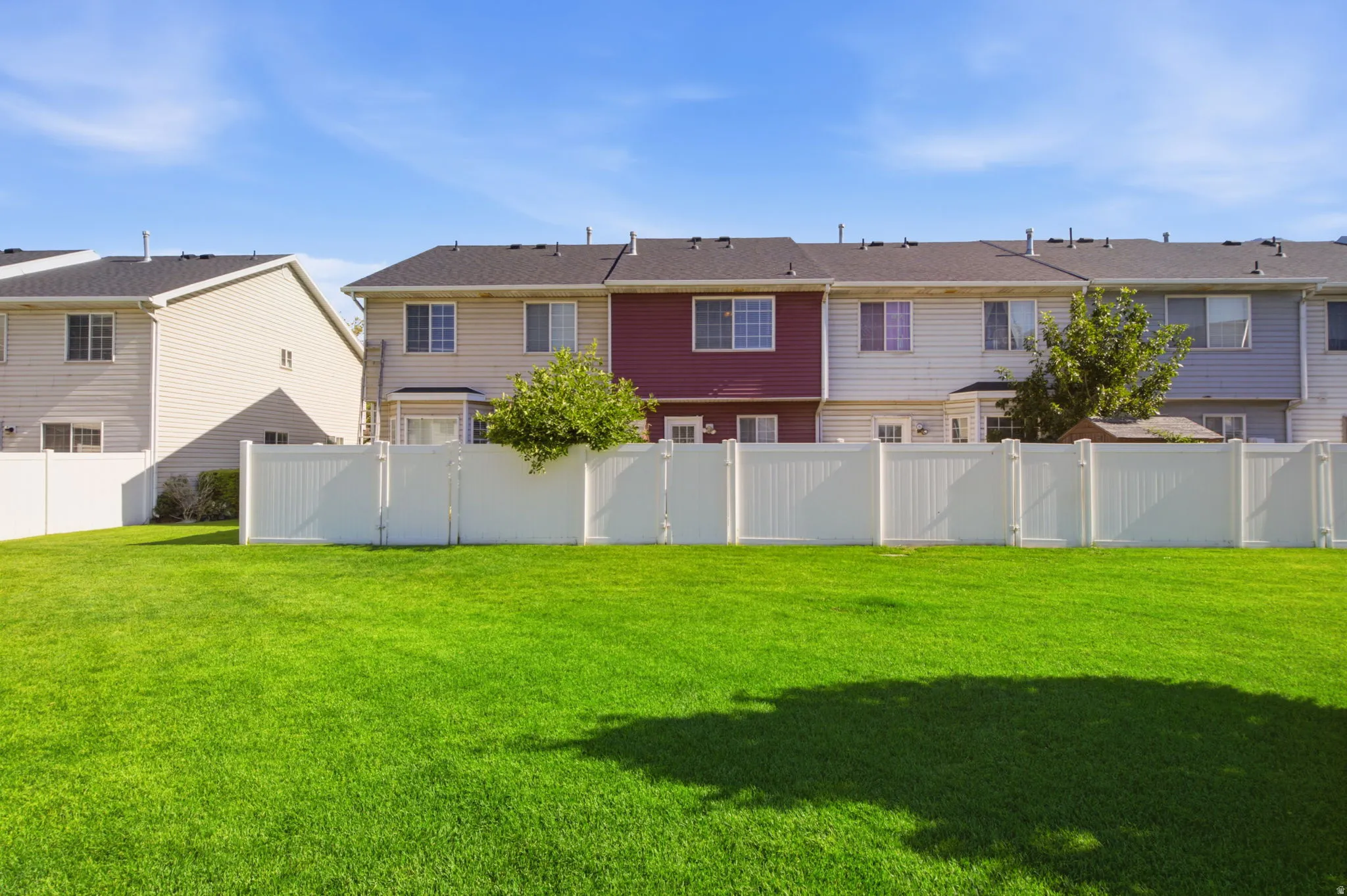 Expansive green lawn area featuring a white privacy fence