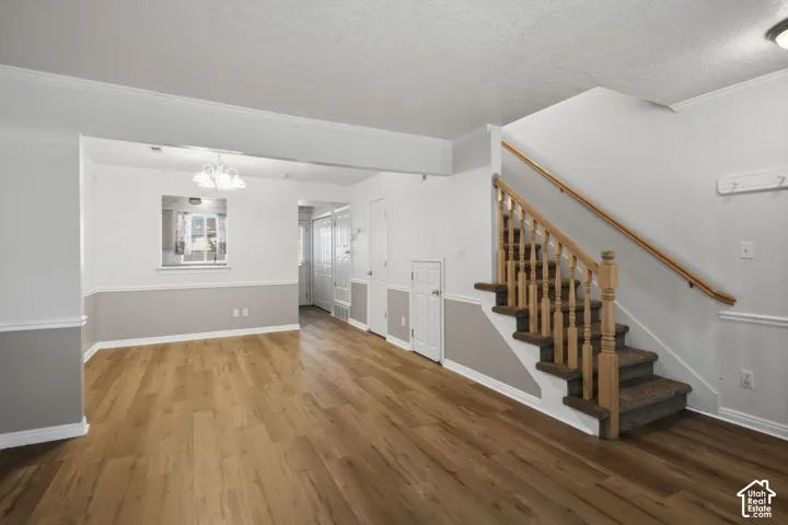 Open-concept living area with wood-finish flooring, two-tone painted walls, and crown molding