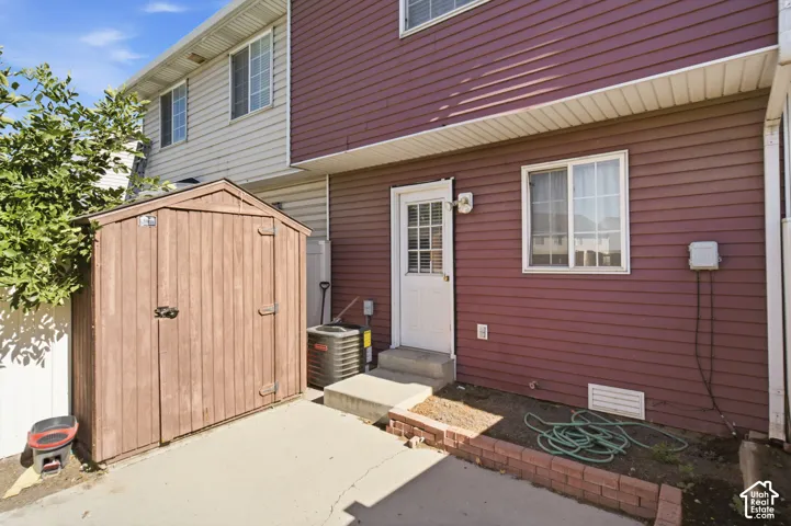 Private patio area featuring a storage shed, concrete pad, and brick-edged planting bed