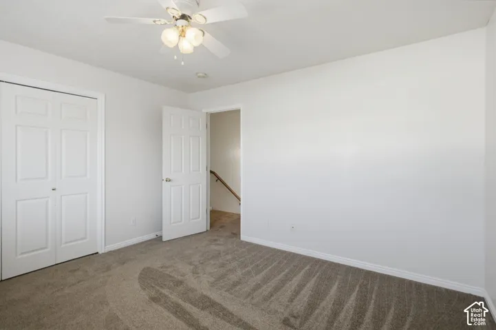 Neutral-toned carpeting in a room featuring a white ceiling fan with integrated lighting