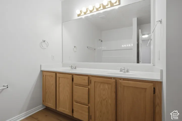 Double vanity with light wood cabinetry, white countertops, and chrome fixtures