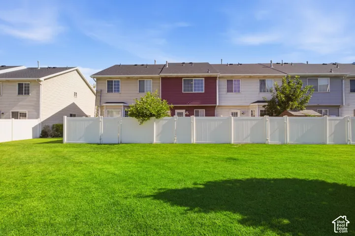Expansive green lawn area featuring a white privacy fence