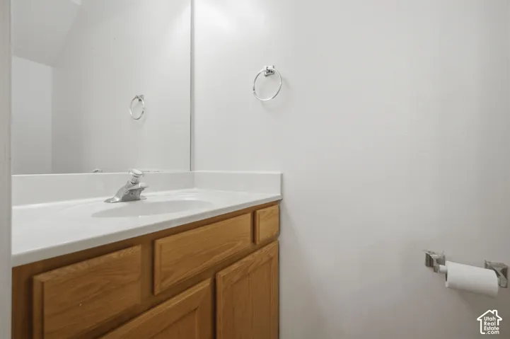 Bathroom vanity featuring a light wood-finish cabinet with panel doors, a white countertop with an integrated sink, and a chrome single-handle faucet