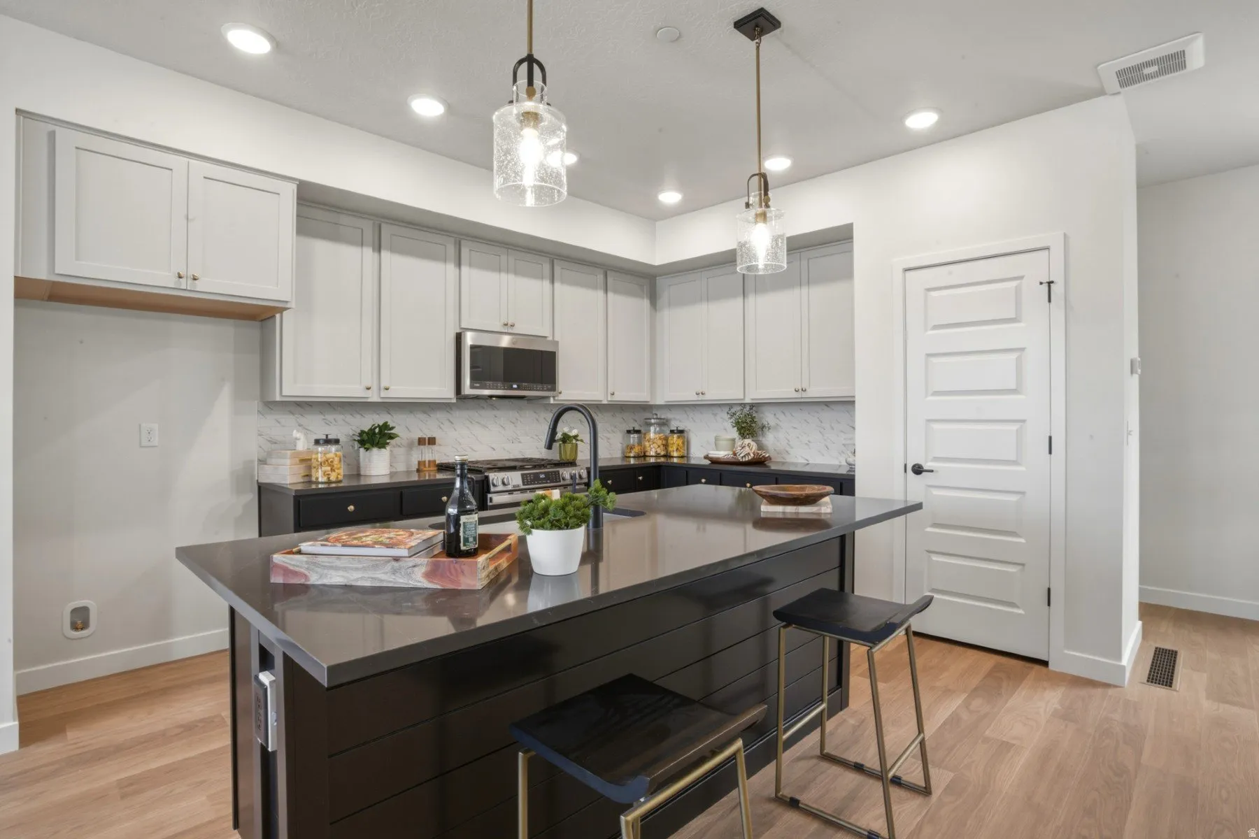 Kitchen featuring a central island with countertop seating, light wood-finish flooring, recessed lighting, and modern pendant fixtures