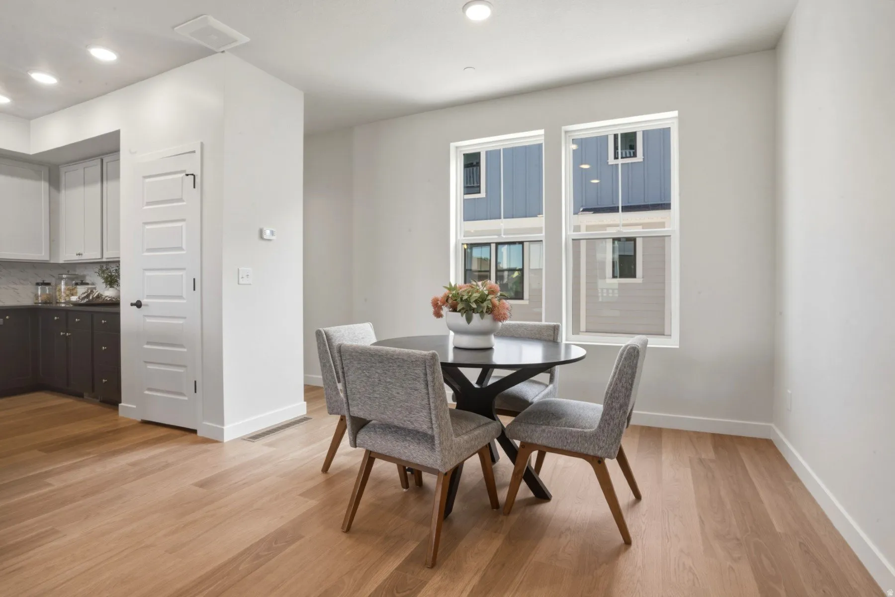Bright interior space featuring wood-finish flooring, two large windows, white baseboards, and recessed lighting