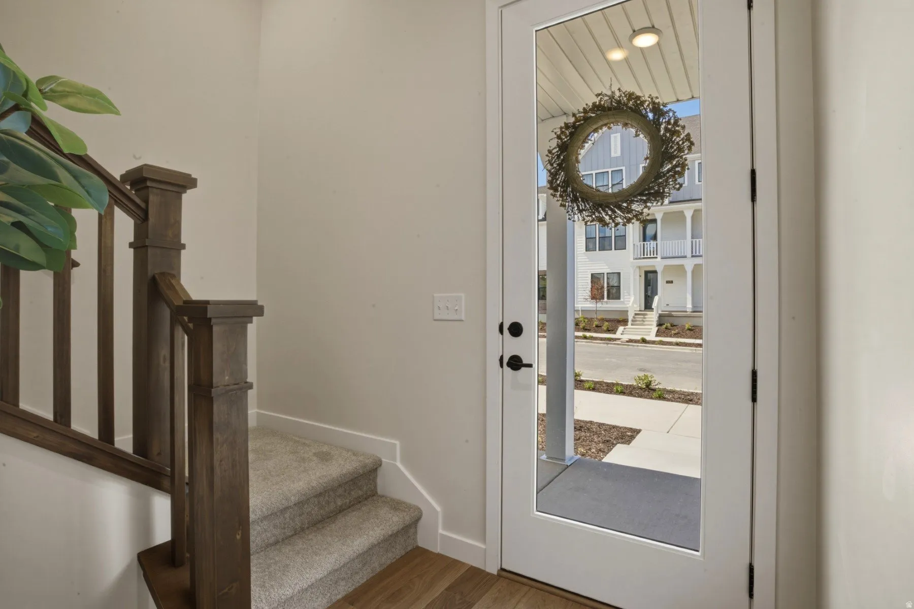 Entryway featuring a full-light door with clear glass, a wood-finish staircase railing, and carpeted stairs