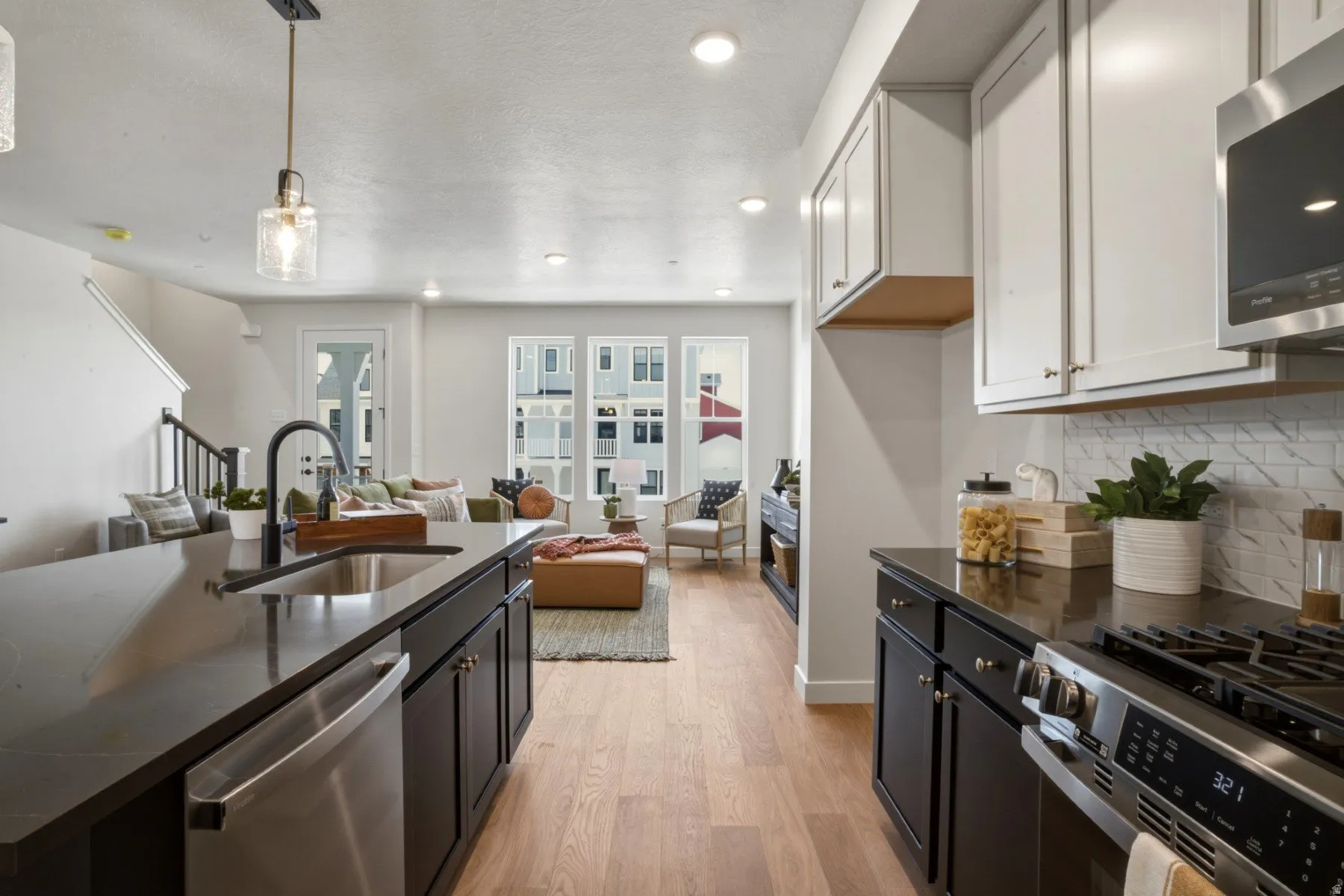 Kitchen featuring dark cabinetry, stainless steel appliances including a dishwasher and gas range, and a rectangular sink with a matte black faucet