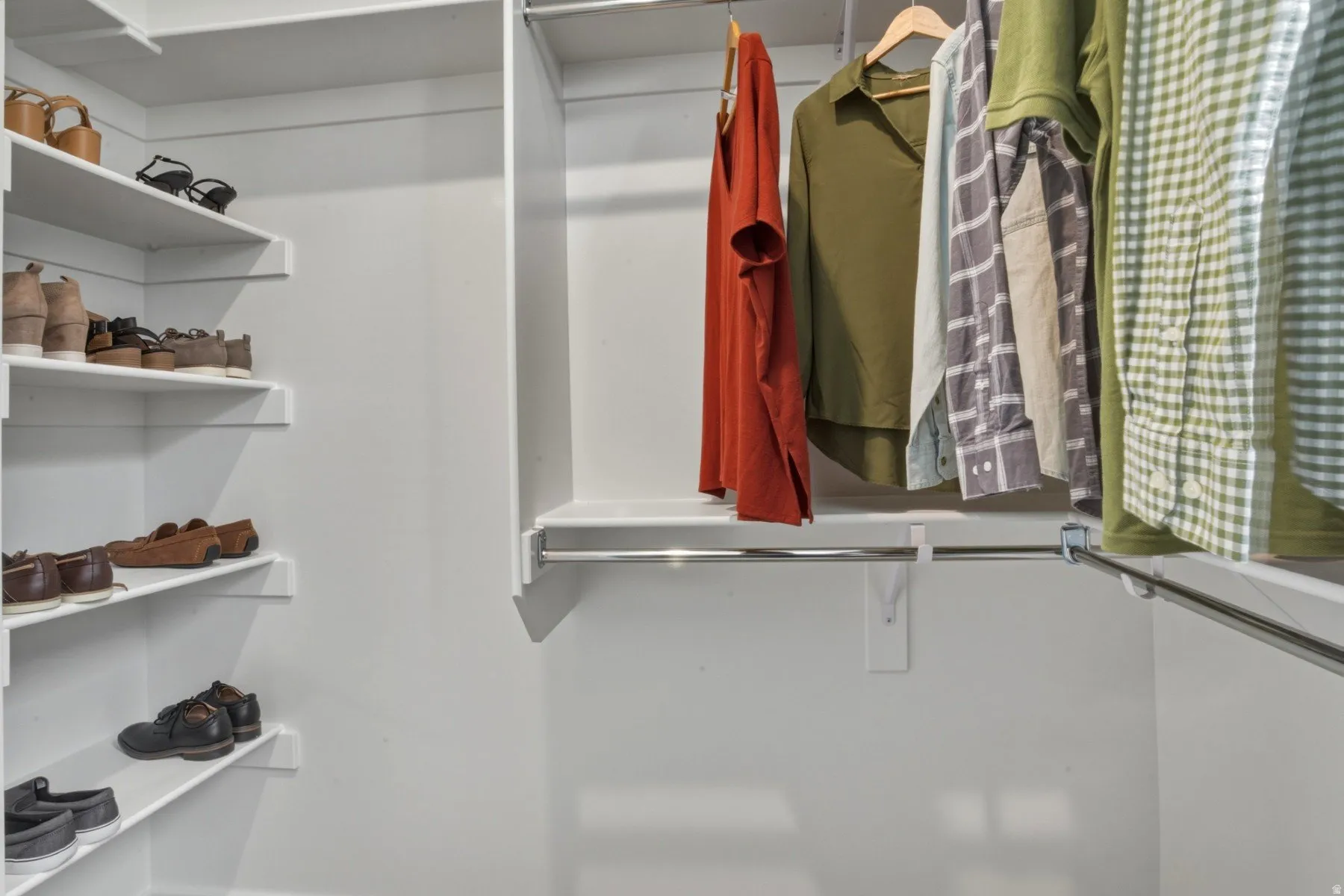 Integrated closet organization system featuring white shelving, multiple hanging rods, corner shelving, and ample storage capacity
