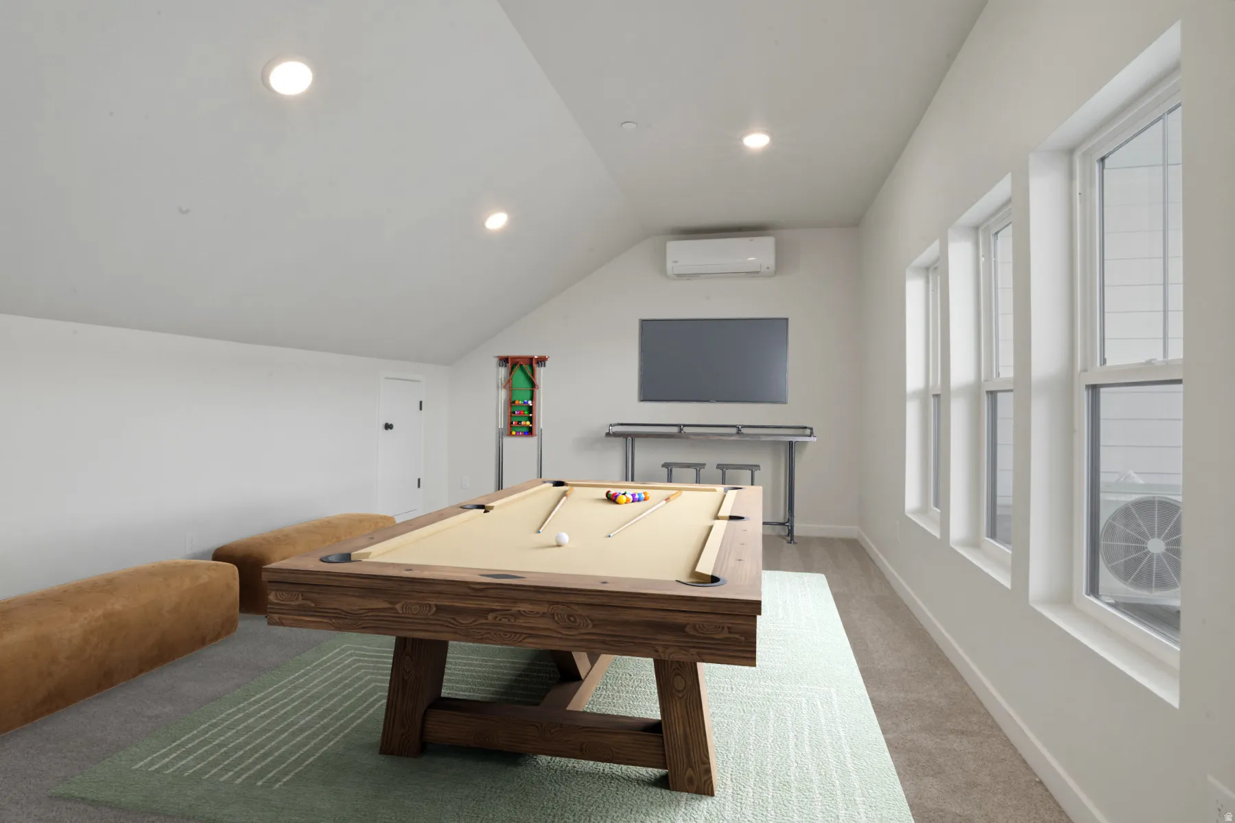 Spacious bonus room featuring a sloped ceiling with recessed lighting, three tall windows, a built-in wall-mounted television, and a mini-split HVAC unit