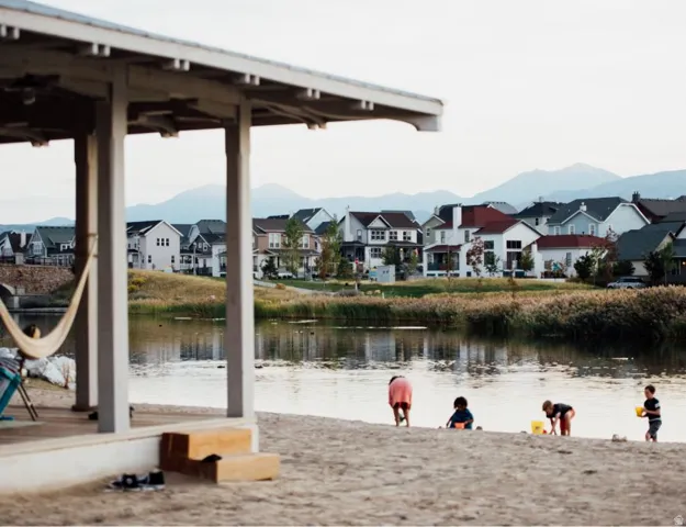 Lakeside community featuring a sandy beach area and a covered pavilion with a hammock