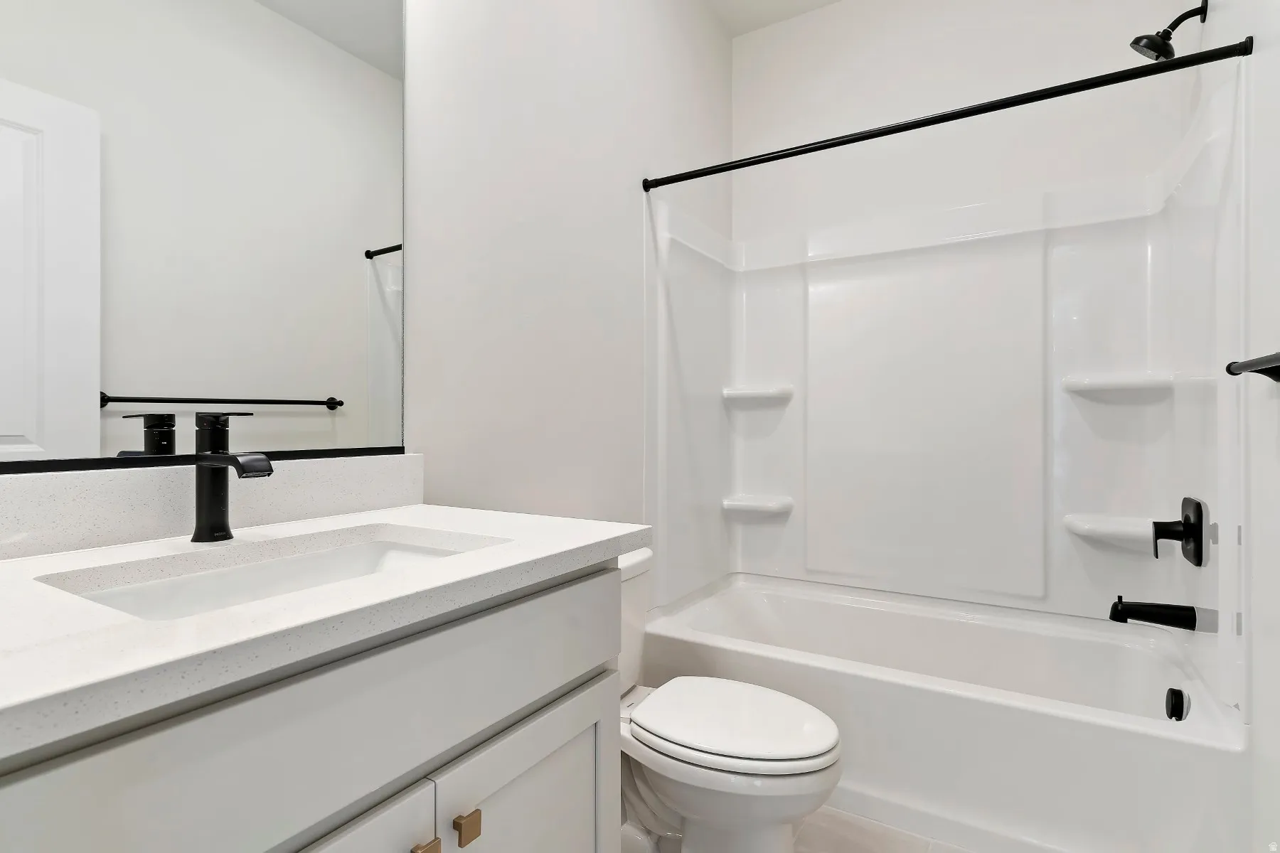Bathroom featuring a white vanity with an integrated sink, a quartz-finish countertop, and a matte black faucet