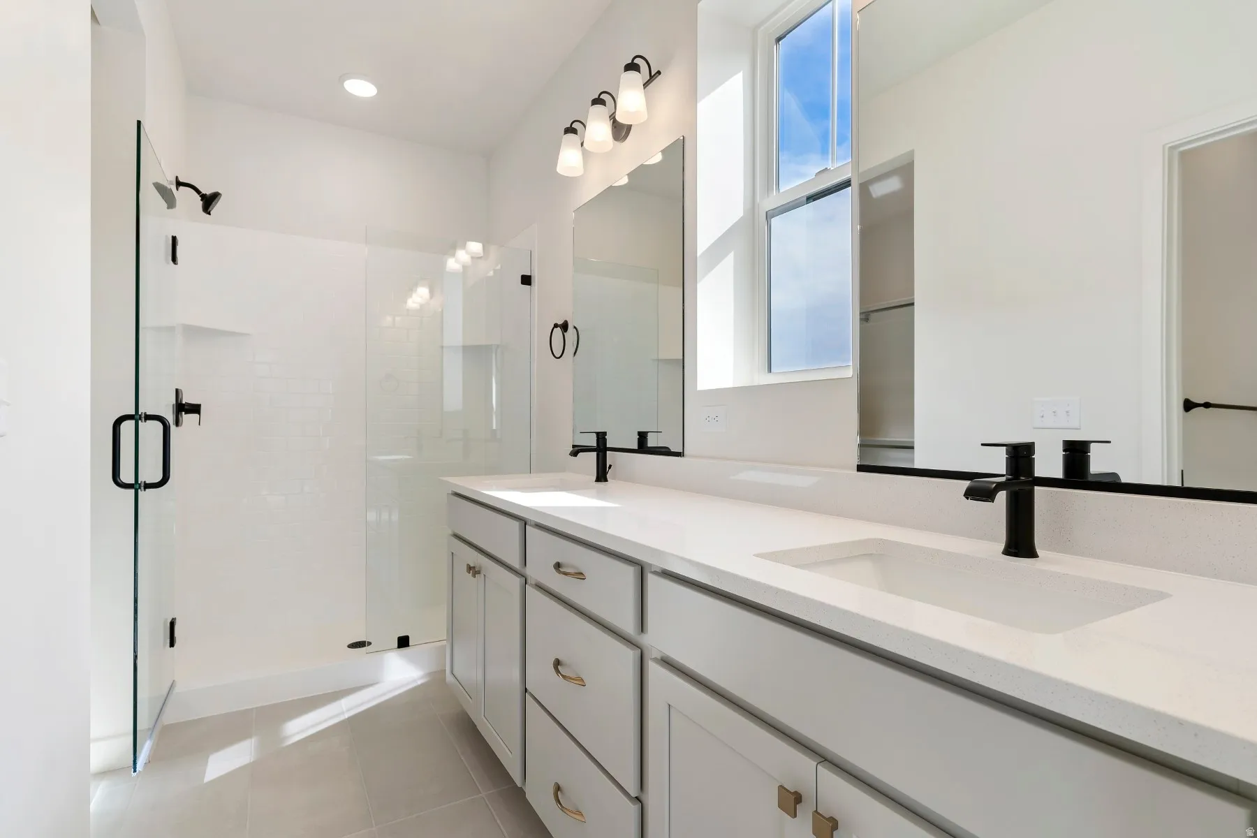 Modern bathroom featuring dual undermount sinks, quartz countertops, and matte black fixtures