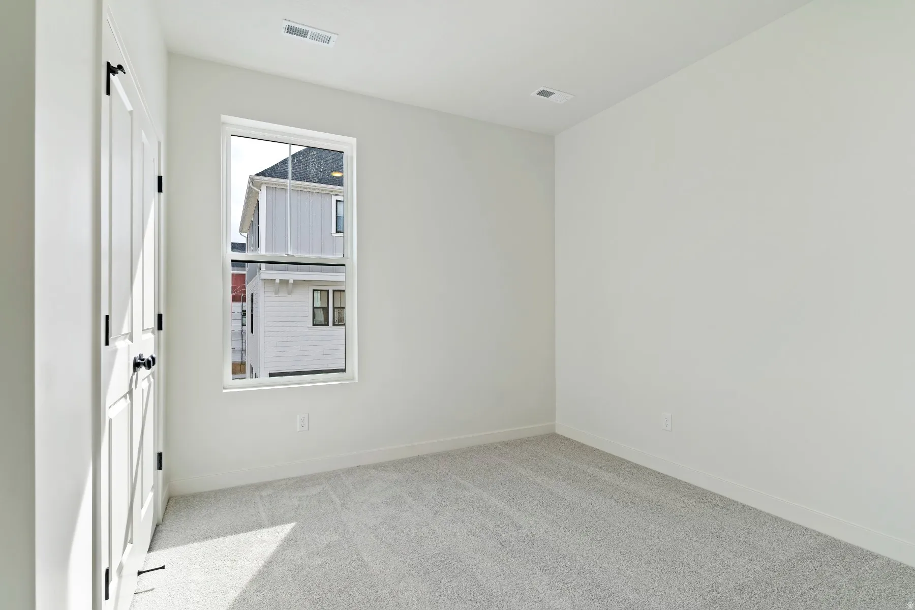 Bright room with a single pane window, light gray carpet, and white walls