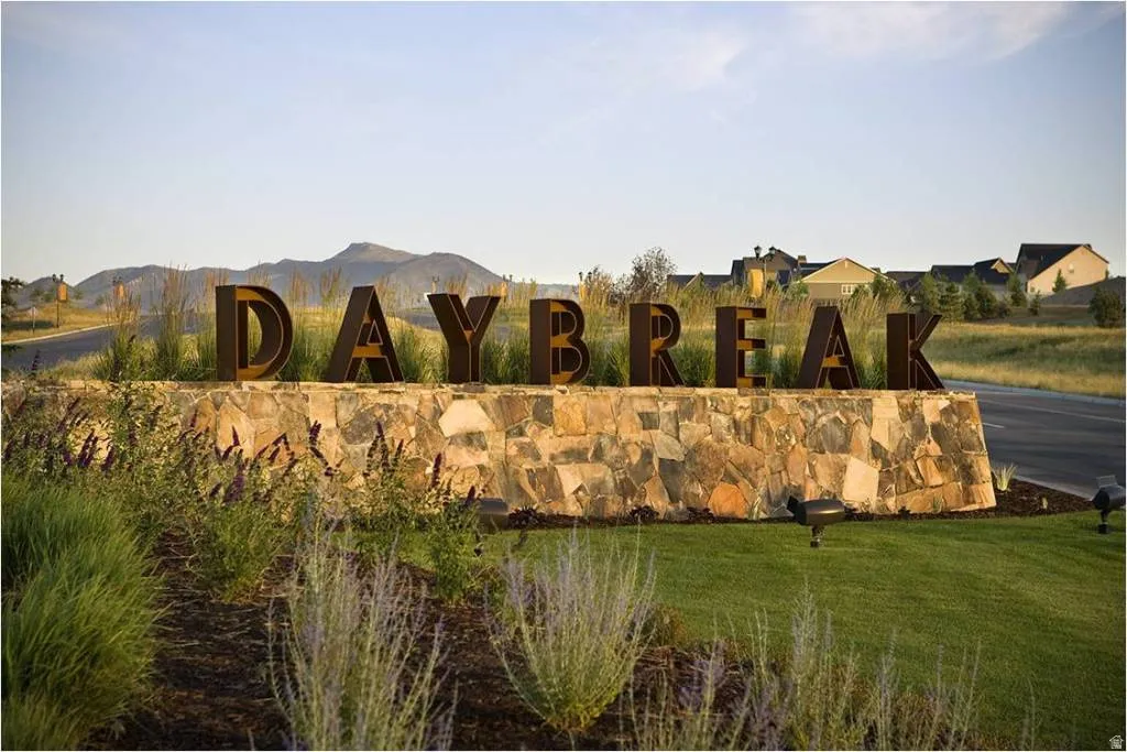 Custom metal lettering atop a stacked stone monument, flanked by a manicured lawn and varied plantings