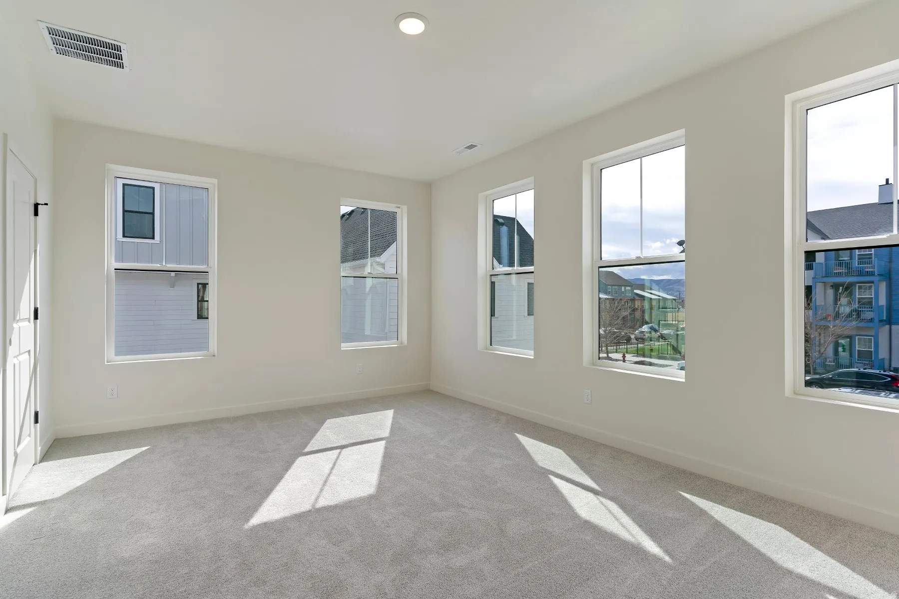 Bright interior space featuring multiple windows, neutral wall tones, light gray carpeting, and a recessed ceiling light