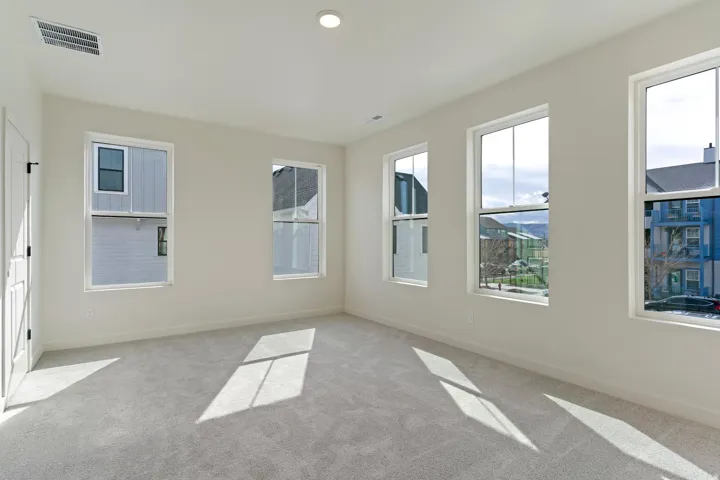Bright interior space featuring multiple windows, neutral wall tones, light gray carpeting, and a recessed ceiling light