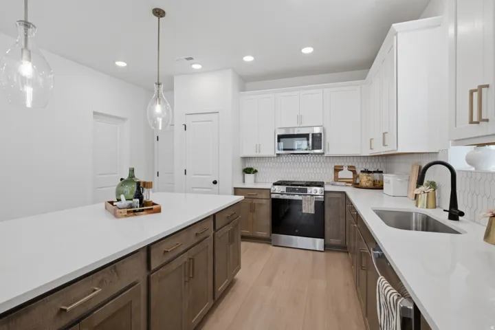 Kitchen featuring an island with stone countertops, two-tone cabinetry, stainless steel appliances, and a tiled backsplash