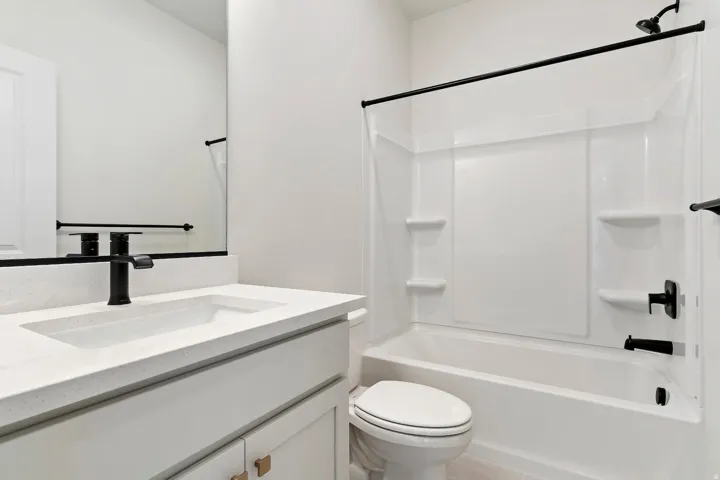 Bathroom featuring a white vanity with an integrated sink, a quartz-finish countertop, and a matte black faucet