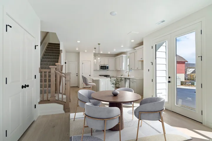 Open-concept living area featuring light wood-finish flooring, white cabinetry, and a kitchen island with seating