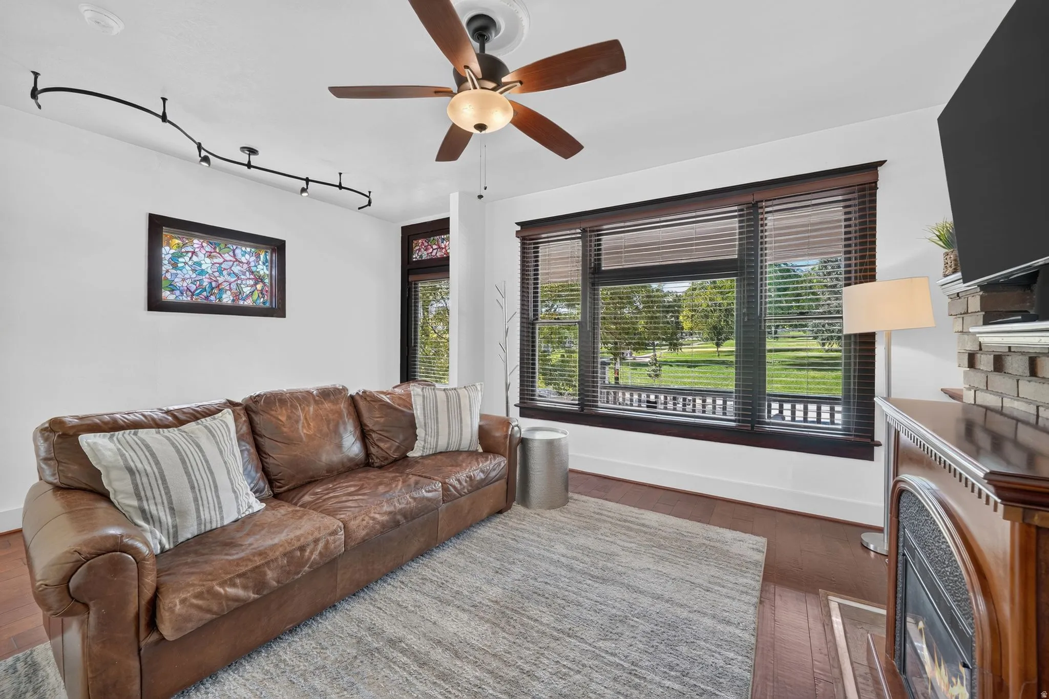Bright living space featuring laminate flooring, a ceiling fan, and track lighting